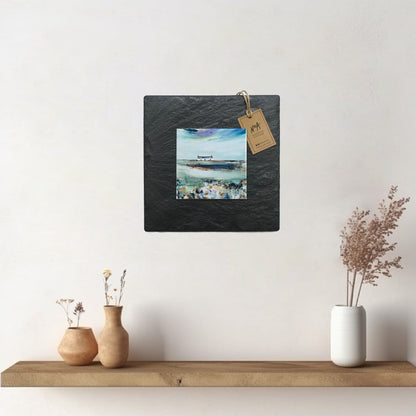 A ceramic tile print of a colourful painting titled 'Spring Days', showing a small house nestled in the Scottish Highlands, available mounted on natural slate or framed.