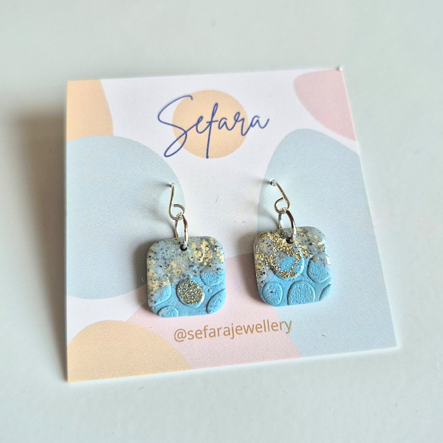 Blue Sand square drop earrings with gold accents on a 'Sefara' branded card.
