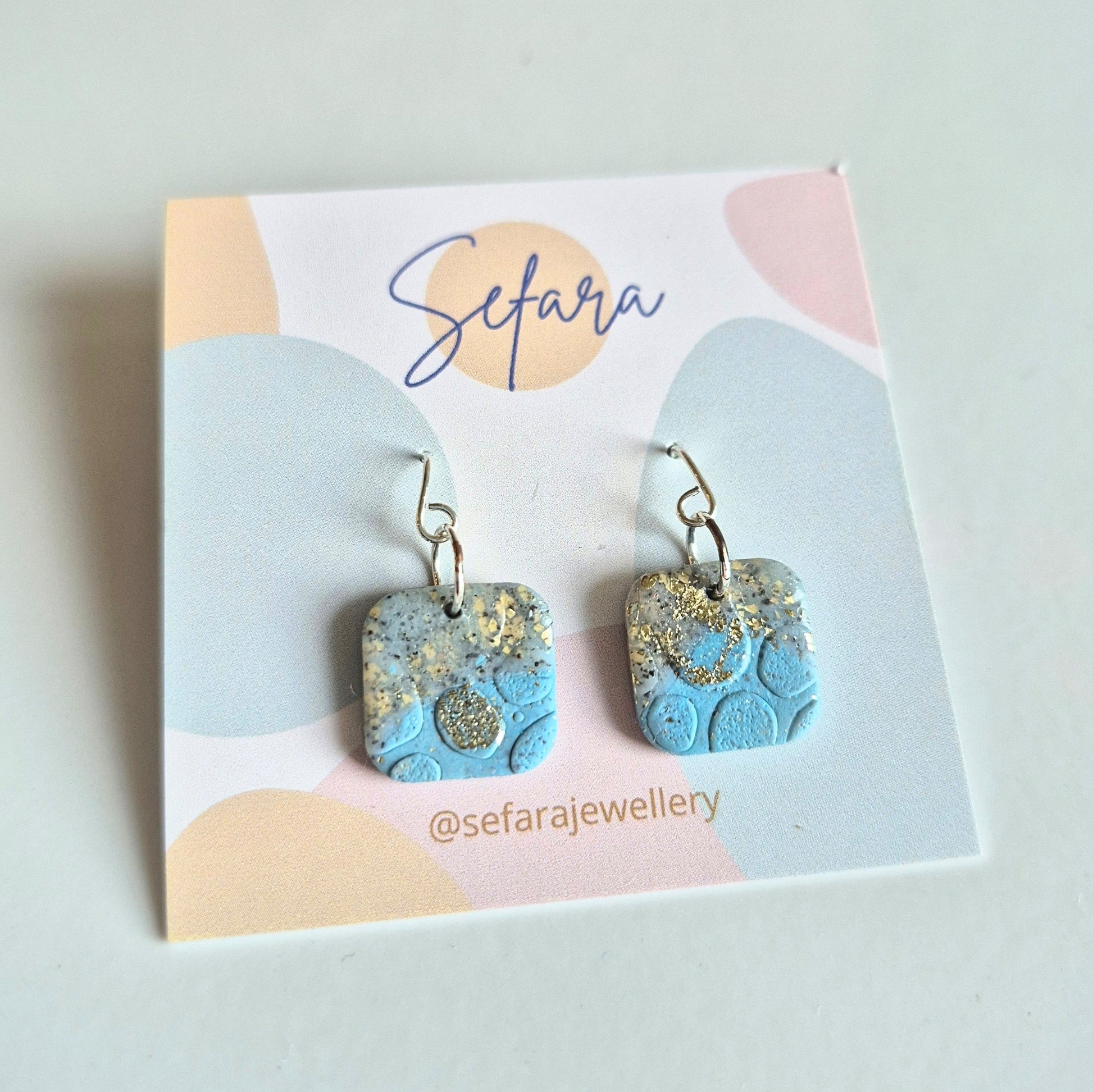 Blue Sand square drop earrings with gold accents on a 'Sefara' branded card.