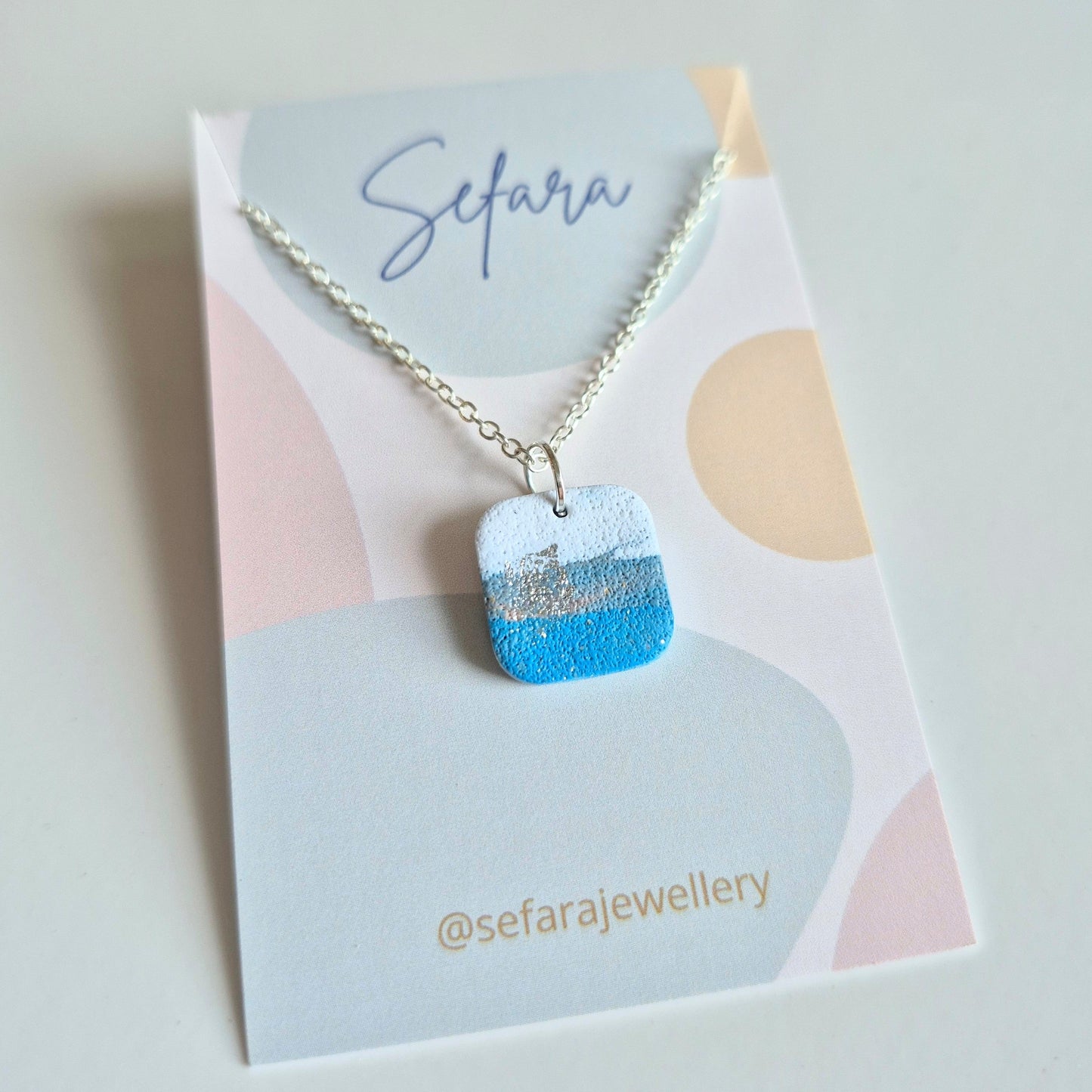 Blue Sky Sea square necklace with a unique design on a Sefara branded card