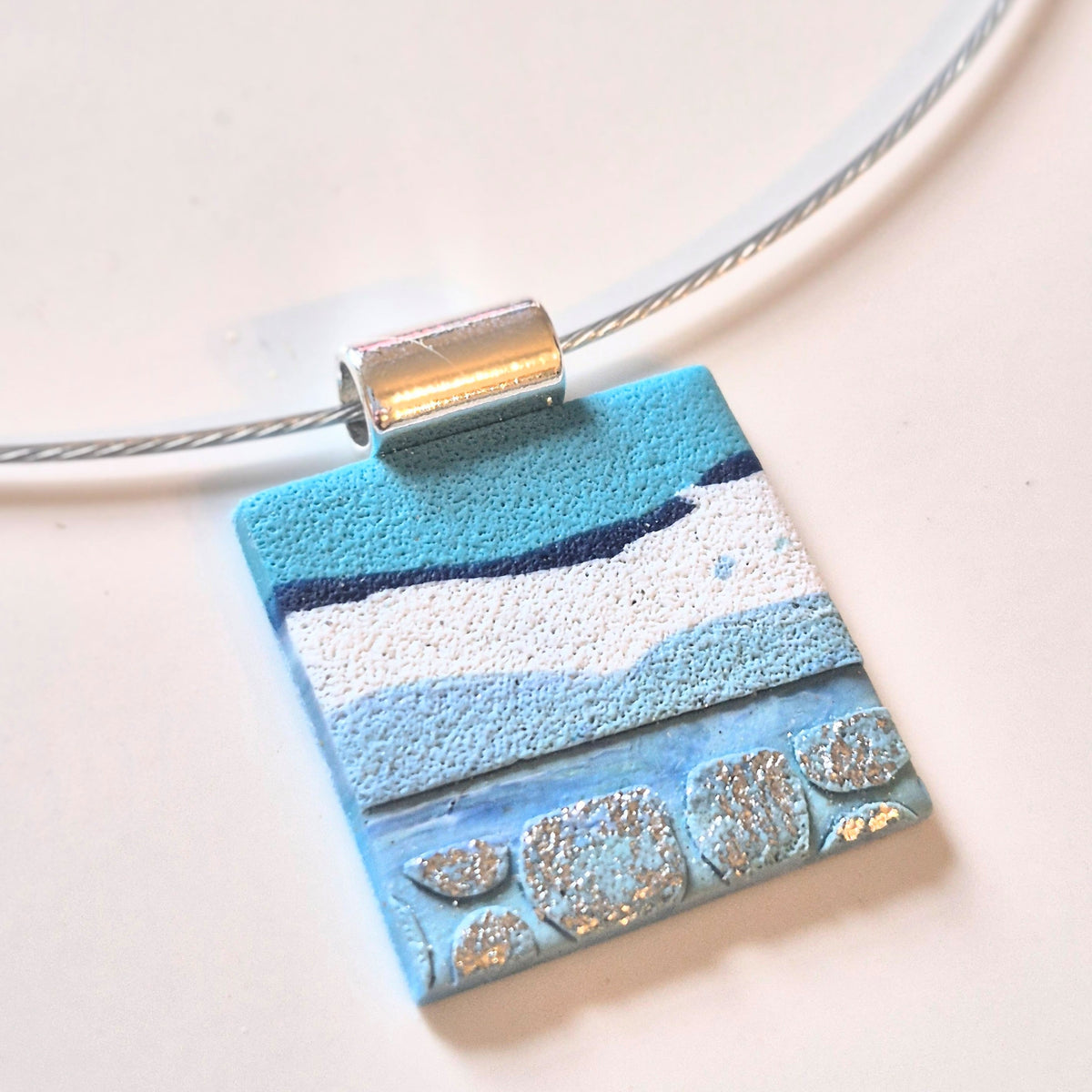 Sefara Jewellery coastal seascape pendant necklace with gold leaf detailing, featuring unique 30mm pendants on silver or black stainless steel chokers.