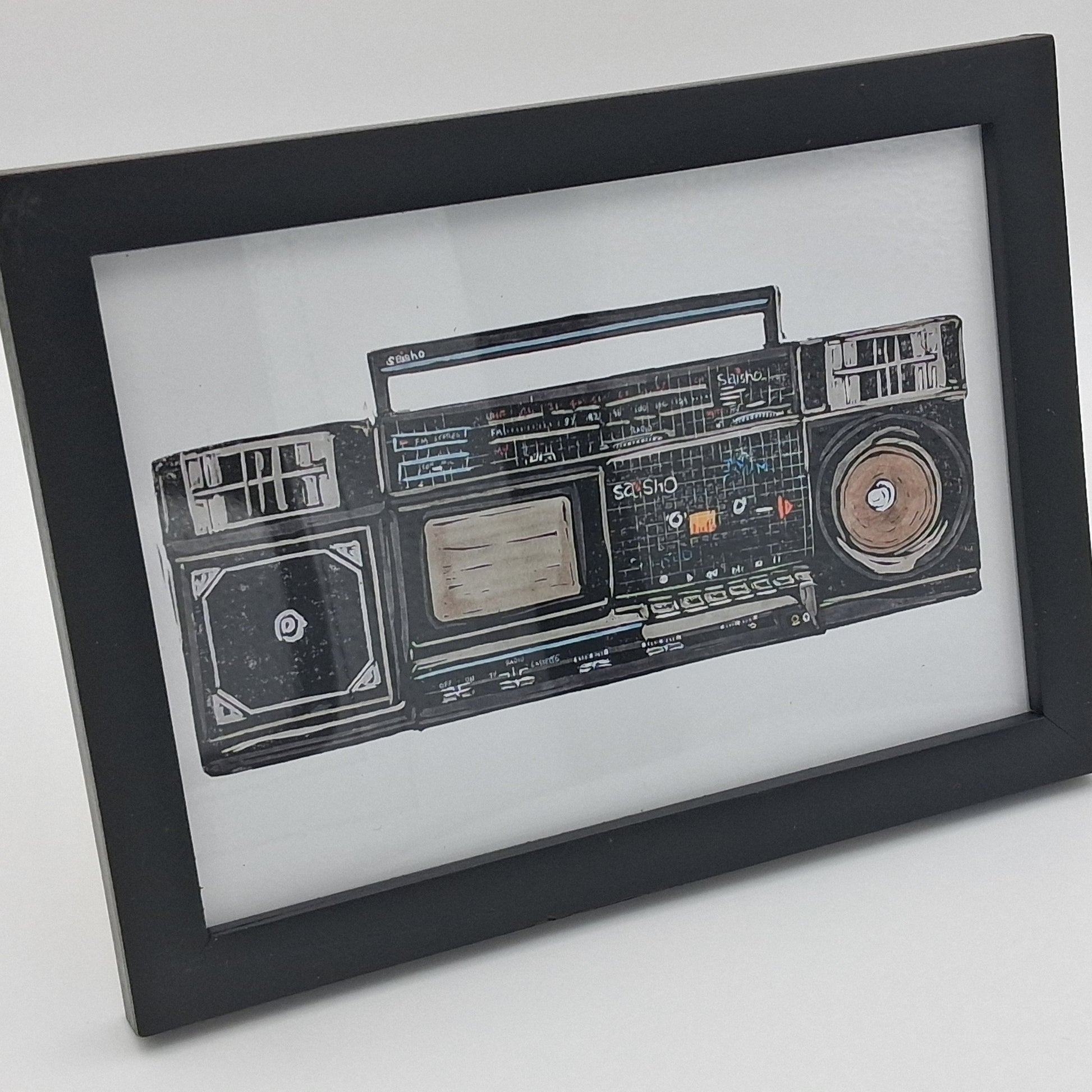 A colourful linocut print depicting a retro 1980s Saisho boom box tape recorder radio, mounted in a small black frame.