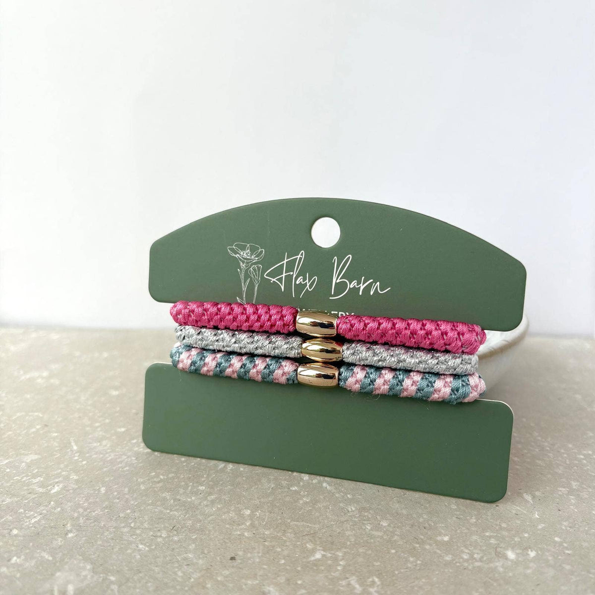 Flax Barn pack of three waterproof elasticated cord hairbands presented on a display card, available in four colourways.