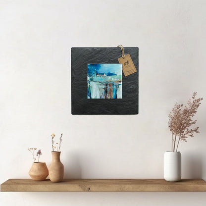 A ceramic tile print of a colourful painting titled 'The Getaway', showing a small house nestled in the Scottish Highlands, available mounted on natural slate or framed.