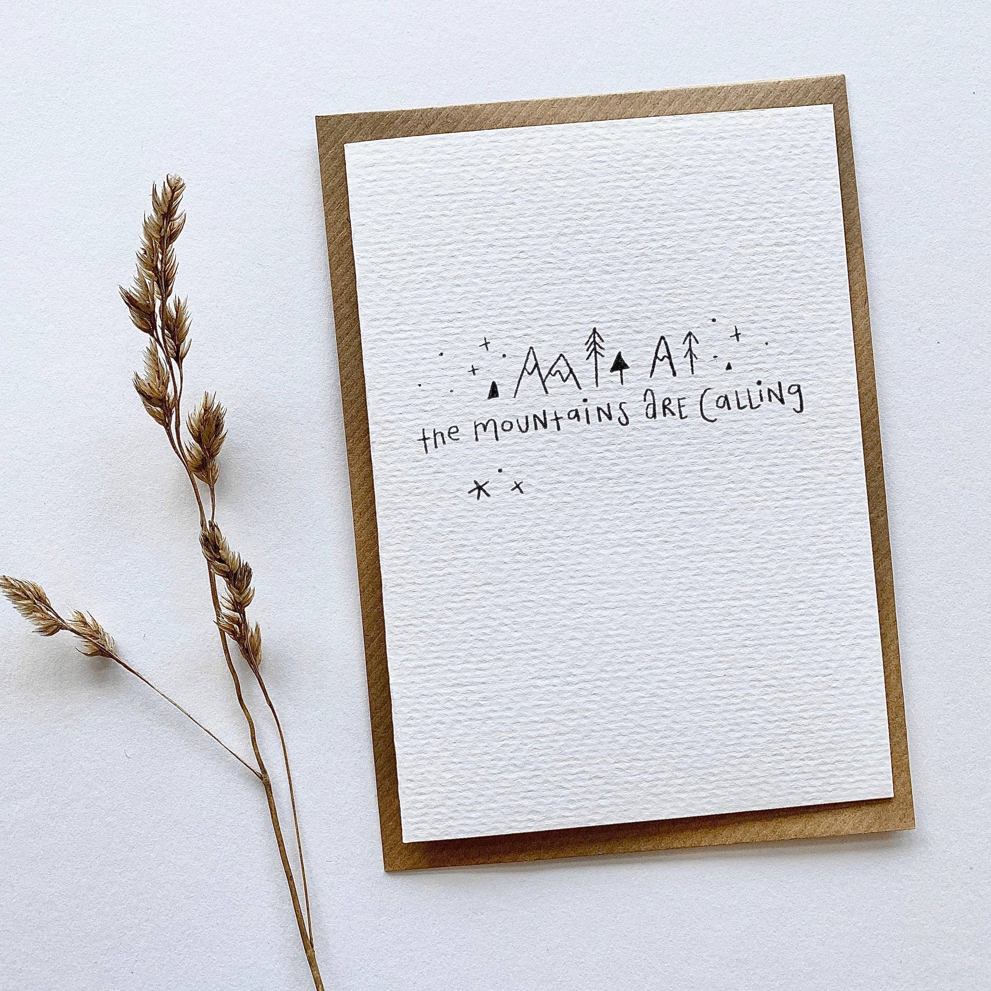 Juniper Press greeting card with 'The Mountains Are Calling' text and minimal mountain-like designs