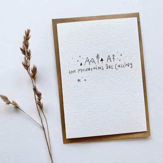 Juniper Press greeting card with 'The Mountains Are Calling' text and minimal mountain-like designs