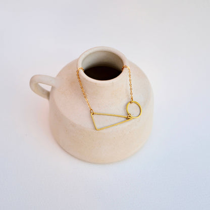 Copper Bee geometric necklace with polished brass circle and triangle shapes on a fine gold-plated chain