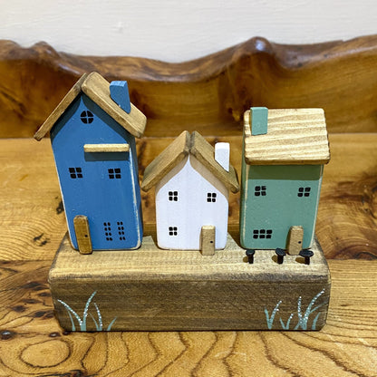 Handcrafted trio of wooden houses on block with rustic metal details in blue, white and green.