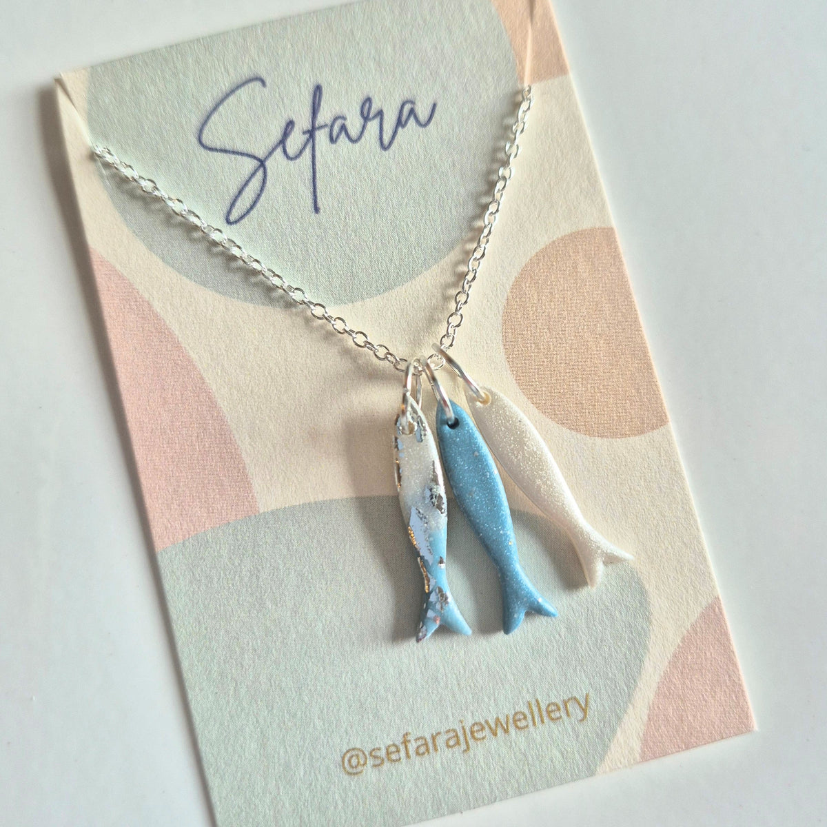 Necklace with three fish charms on a 'Sefara' branded card