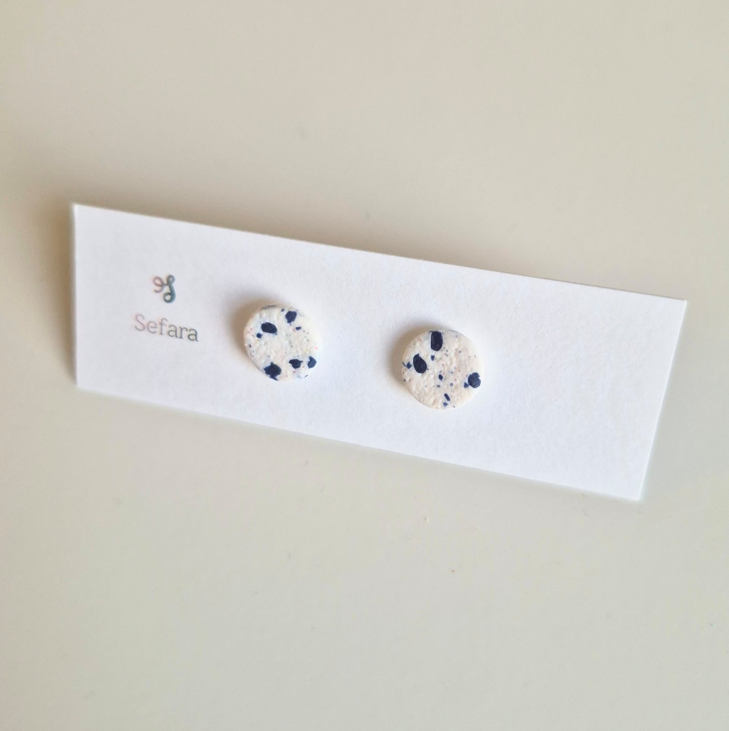 White and Navy Sefara round stud earrings on a branded card