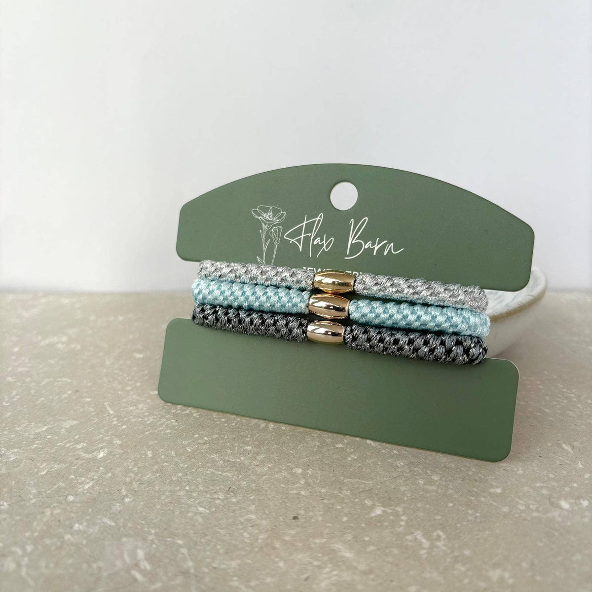 Flax Barn pack of three waterproof elasticated cord hairbands presented on a display card, available in four colourways.