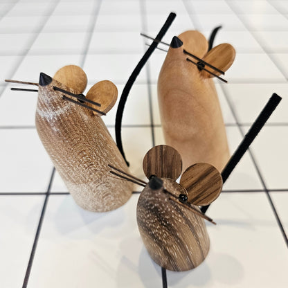 A collection of small, medium, and large decorative mice, each one uniquely carved from local wood, standing upright with small eyes, ears and whiskers