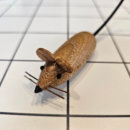 A decorative mouse uniquely carved from local wood with small eyes, ears, whiskers and a leather tail