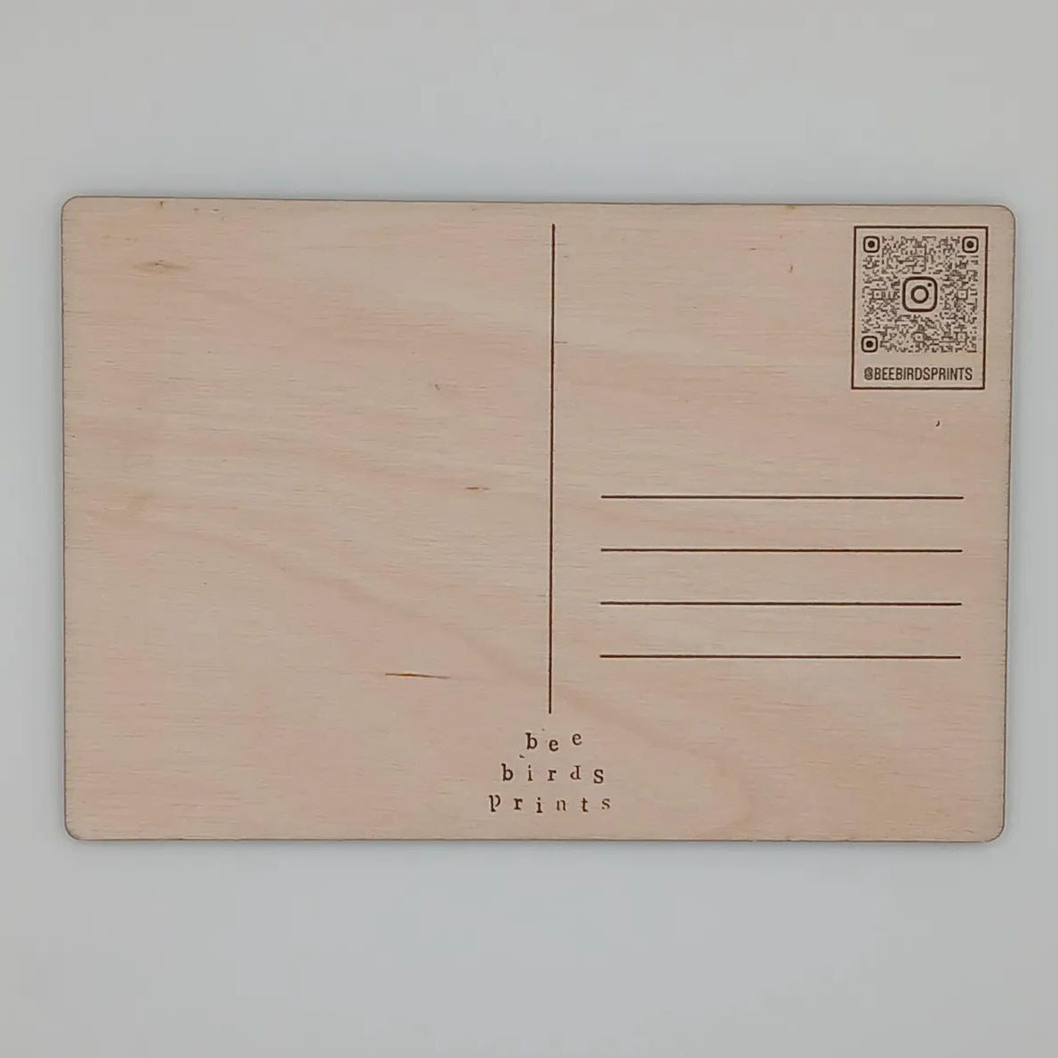 Back of wooden postcard featuring a unique colourful lino cut image of a cycling-related scene or landscape.