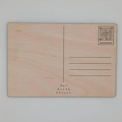 Back of wooden postcard featuring a unique colourful lino cut image of a cycling-related scene or landscape.