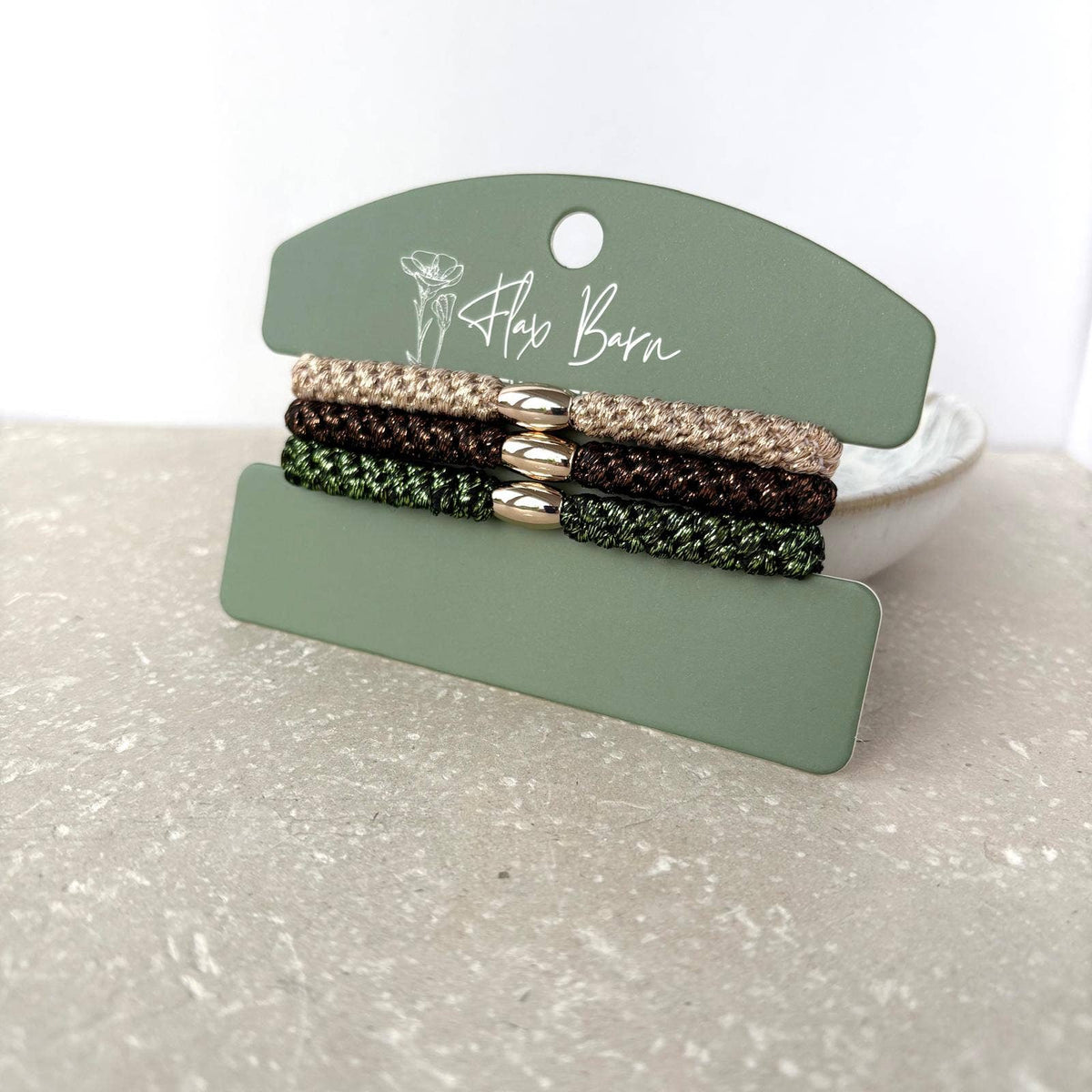 Flax Barn pack of three waterproof elasticated cord hairbands presented on a display card, available in four colourways.