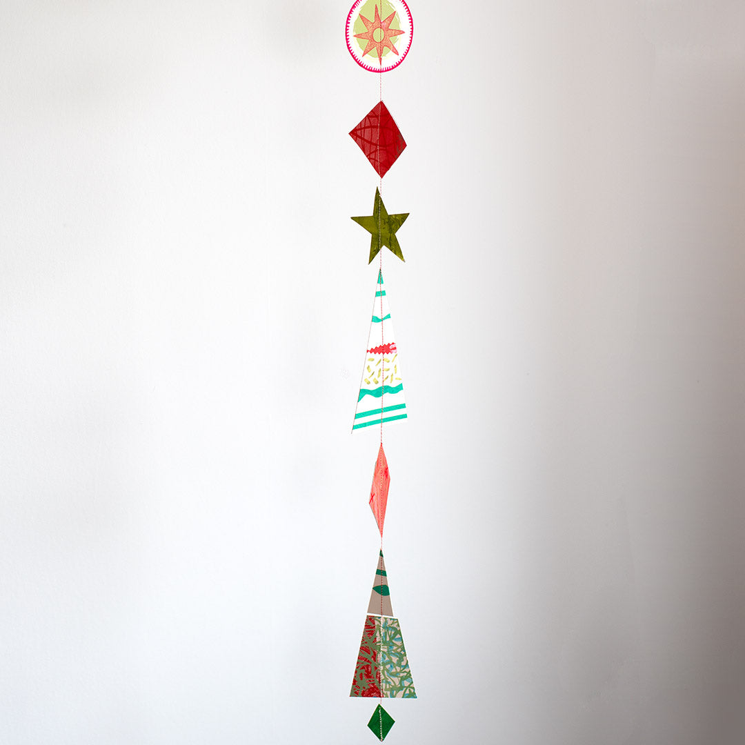Vertical hanging Christmas garland made of 12 colourful, modern shapes cut from recycled and hand-painted card prints.