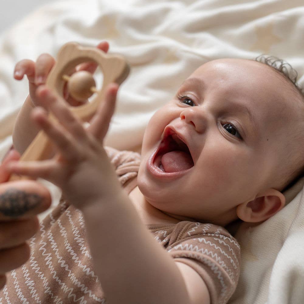 Baby holding a Ziggle wooden rattle