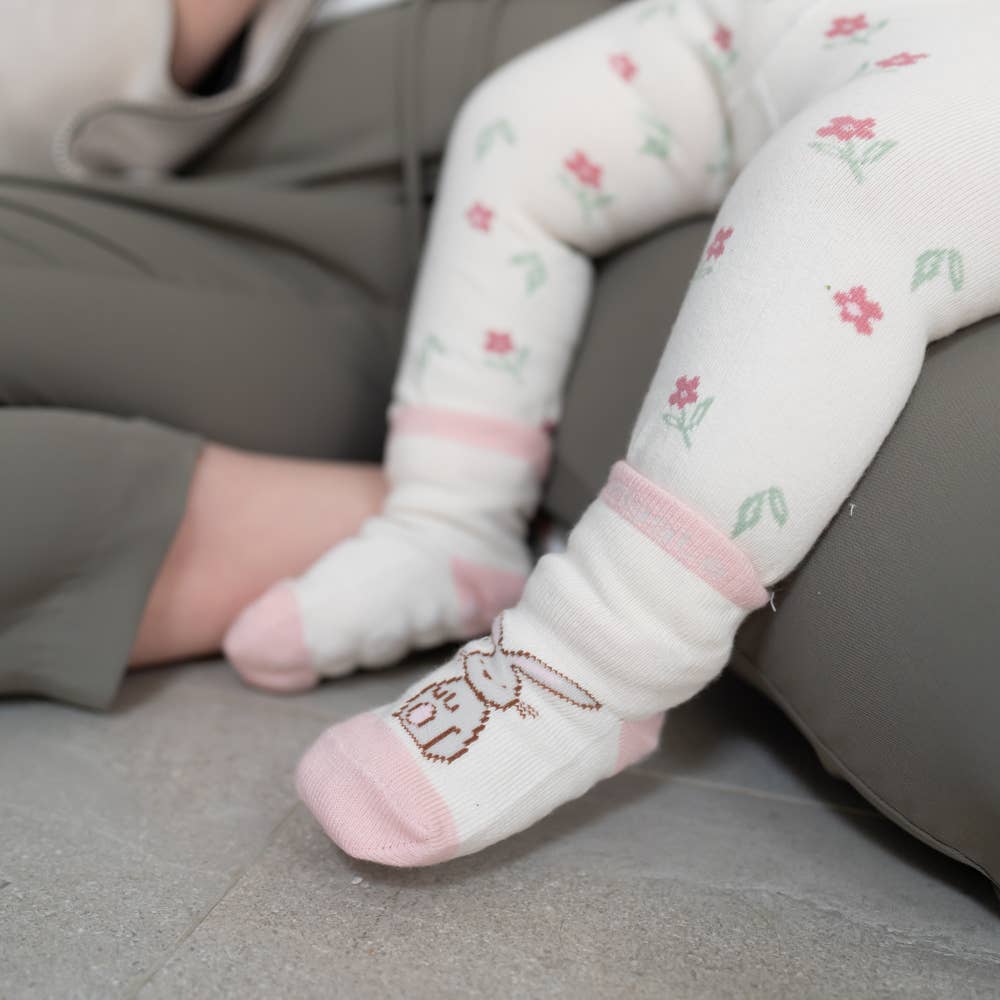 Baby's feet wearing pink cotton baby socks with bunny design, anti-slip soles and ribbed cuffs