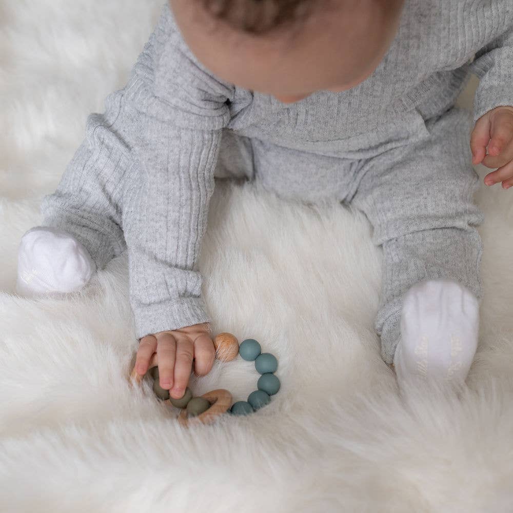 Baby holding a Ziggle wooden teether in Blue Grey