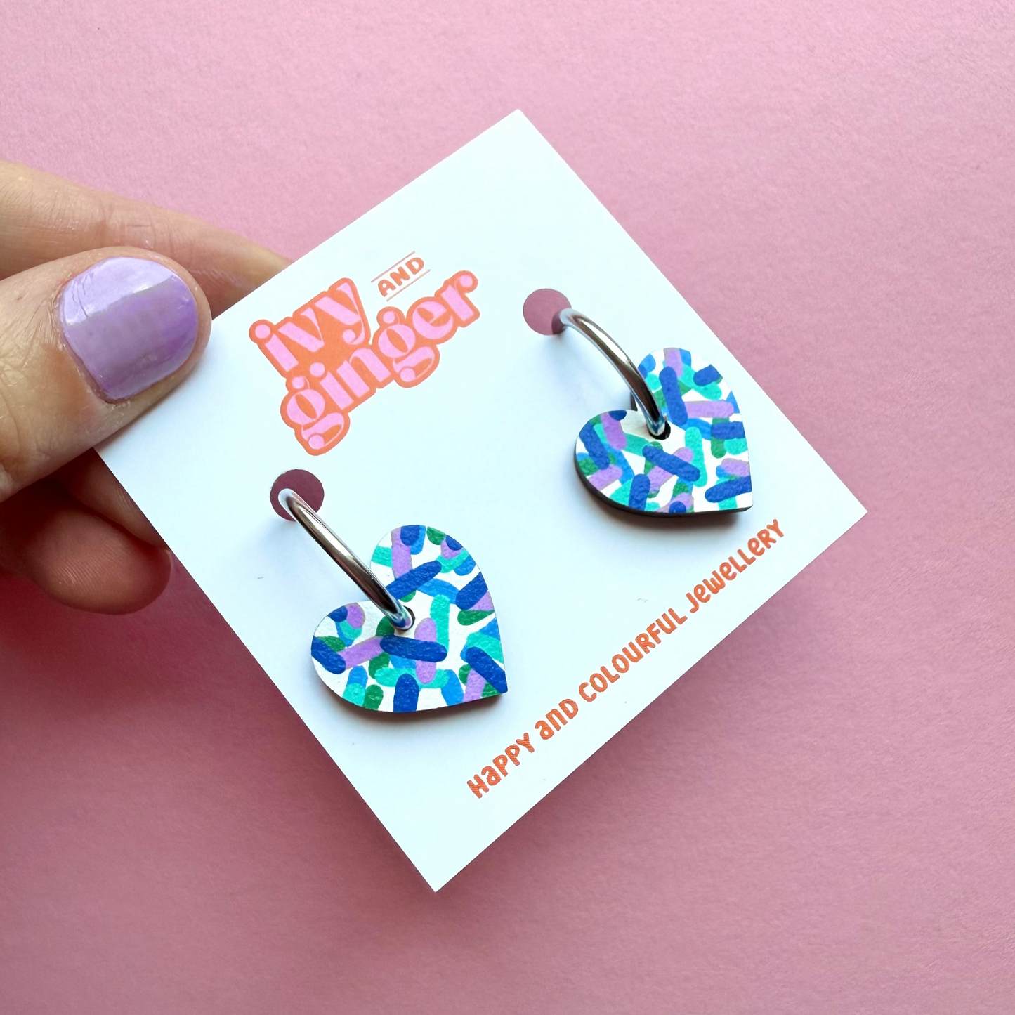 Hand painted white heart-shaped wooden hoop earrings with colourful confetti print, FSC wood, surgical steel lever back, 20mm, lightweight and gift-ready.