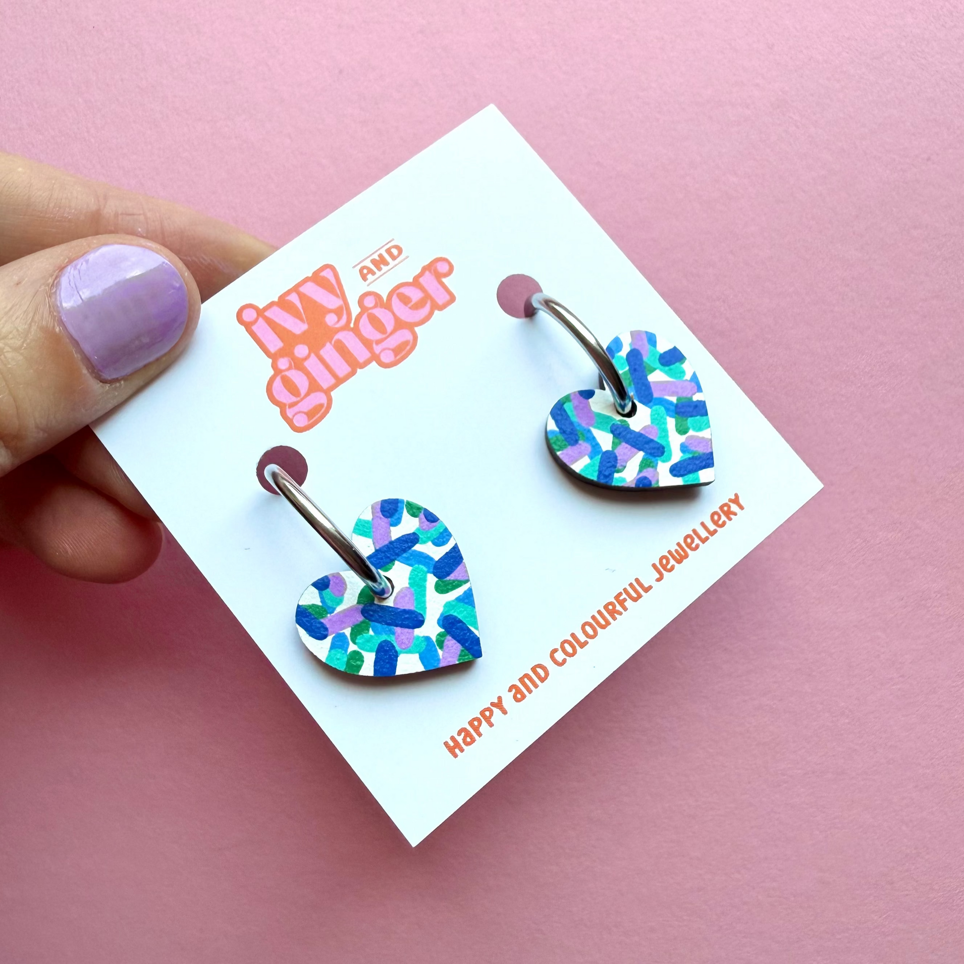 Hand painted white heart-shaped wooden hoop earrings with colourful confetti print, FSC wood, surgical steel lever back, 20mm, lightweight and gift-ready.